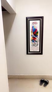 a picture on a white wall with two shoes on the floor at 15c sunset lane 8 in Karachi