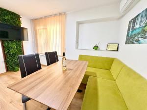 ein Esszimmer mit einem grünen Sofa und einem Holztisch in der Unterkunft City Charm Apartments 2 in Warna