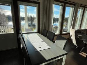 a dining room with a table and chairs and windows at Rantatähti Villa in Syöte