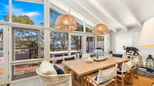 ein Esszimmer mit Tisch und Stühlen und Fenstern in der Unterkunft 'Hampton Cottage' By HolidayCo in Pretty Beach