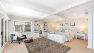 a bedroom with a bed and a chair in a room at 'Hampton Cottage' by HolidayCo in Pretty Beach