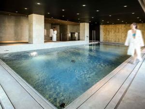 ニオールにあるIbis Niort Est Mendes Franceの女性がホテルのプールのそばを歩いている