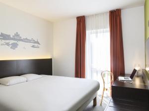 a bedroom with a bed and a desk with a laptop at Ibis Styles La Louvière in La Louvière