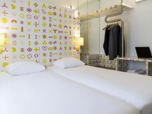 a bedroom with a bed and a wall with symbols on it at Ibis Styles La Louvière in La Louvière +140 photos