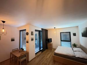a bedroom with a bed and a table and two windows at Island Safehouse in Olomouc
