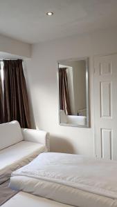 a white bedroom with a bed and a mirror at Number 5 in Harwich