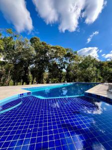 a blue tile swimming pool with a blue sky at Chalés Nascente Tietê in Salesópolis