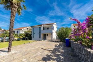 a villa with a palm tree and a driveway at Modern Villa Christian with pool, sauna, and jacuzzi, 10 min walk from the beach in Malinska