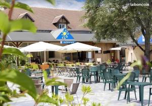 an outdoor patio with tables and chairs and umbrellas at Mobil-home Excellence - 3 Chambres in Chaumont-sur-Loire