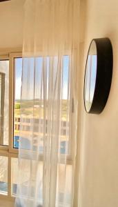 a window with a white curtain and a mirror at beachfront apartment with pool in Porlamar in Porlamar