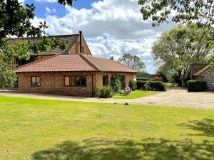une maison en briques avec une pelouse verte devant dans l'établissement The Granary - Wood Farm Barn. Luxury Barn with wonderful countryside views, à Bawdeswell