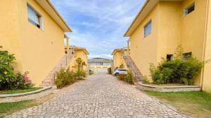 un vicolo acciottolato tra due case gialle di Residencial IL Pevero, condomínio com piscina e área gourmet a uma quadra da Praia de Taperapuã aptos com 2 quartos a Porto Seguro