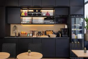 a kitchen with black cabinets and tables and chairs at Hôtel Korner Châtelet in Paris +23 photos