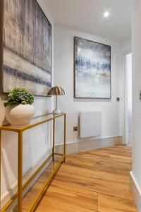 a hallway with a table with a vase on it at NEW! Fulham 1-bed Apartment with Patio in London +1 photo