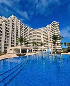 a large hotel with a large swimming pool in front of it at beachfront apartment with pool in Porlamar in Porlamar