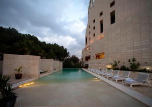 a swimming pool with lounge chairs next to a building at Le Royal Hotel - Amman in Amman