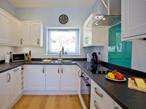 a kitchen with white cabinets and a plate of fruit on the counter at Dunlin 4 - The Cove in Brixham +9 photos