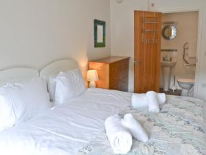 Una cama blanca grande con toallas en un dormitorio en Porhellik, en Zelah