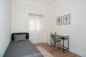 a bedroom with a bed and a desk and a chair at The Family Nest Amadora T4 in Amadora