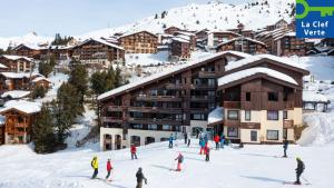 贝勒普拉涅石英皮埃尔假日公寓式酒店的一群人在小屋前的雪中滑雪