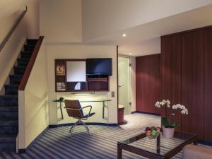 uma sala de estar com uma escada e um quarto com uma cadeira em Mercure Hotel München Airport Freising em Freising mais 45 fotografias