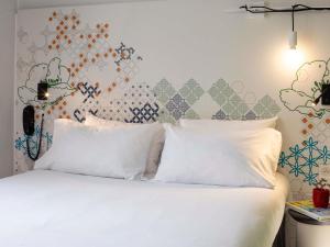 Un dormitorio con una cama blanca con almohadas blancas. en Ibis Styles Paris Gare Saint Lazare, en París
