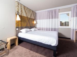 a hotel room with a bed and a window at Ibis Toulouse Purpan Aeroport in Toulouse