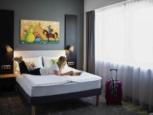 a woman laying on a bed in a hotel room at ibis styles Grudziadz in Grudziądz +91 photos