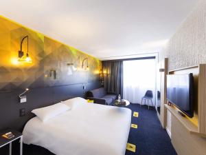 a hotel room with a white bed and a tv at ibis Styles Poitiers Nord in Poitiers