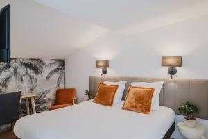 a bedroom with a large white bed with orange pillows at Hôtel Amaya in Ambarès-et-Lagrave