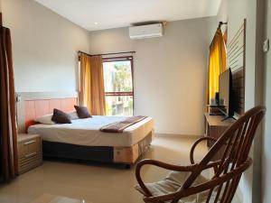 a bedroom with a bed and a chair and a window at Puri Sadewa Balangan in Jimbaran