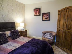 une chambre avec un grand lit et une chaise dans l'établissement Blaeberry Cottage - 28061, à Dinwoodie Mains