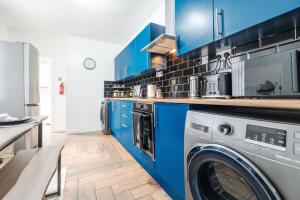 a kitchen with blue cabinets and a washing machine at Newly Renovated 4BR House with lots of amenities in Liverpool +68 photos