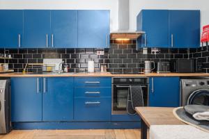 a kitchen with blue cabinets and a black tile wall at Newly Renovated 4BR House with lots of amenities in Liverpool