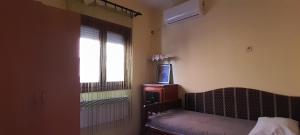 a room with a bed and a window and a television at Airport Guesthouse Rooms and Apartmants in Beograd