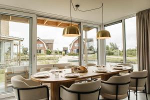 ein Esszimmer mit Tisch und Stühlen und großen Fenstern in der Unterkunft Watervilla binnenhaven met Sauna | 6 personen - Boutique Parc Pharshoeke in Heeg