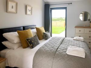 a bedroom with a bed with yellow pillows and a window at The Old Dairy - Uk31253 in Middleton +12 photos