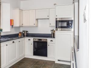 eine weiße Küche mit weißen Schränken und Geräten in der Unterkunft Ringrone 3 in Salcombe