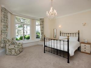 ein Schlafzimmer mit einem Bett, einem Stuhl und einem Kronleuchter in der Unterkunft Ringrone 3 in Salcombe + 9 Fotos