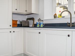 eine Küche mit weißen Schränken und einer blauen Arbeitsplatte in der Unterkunft Ringrone 3 in Salcombe