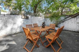 a wooden table with four chairs and a cat sitting on it at Pyrmont NSW - 3 Bedroom Apartment- 8 Guests - NetFlix in Sydney