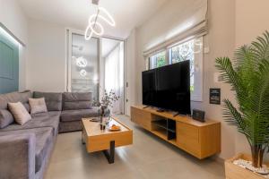 Una sala de estar con un sofá y un televisor de pantalla plana. en Callisto Elegant Apartment Near Acropolis, en Atenas