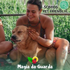 パリョサにあるPousada Magia da Guardaの女が犬の隣に座っている