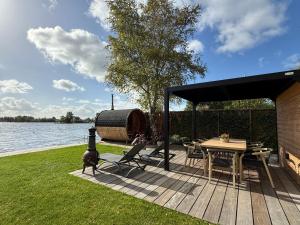 una terraza de madera con una mesa y un barco en Villa Perla Mare - Sauna Experience - On a lake near Amsterdam, en Vinkeveen