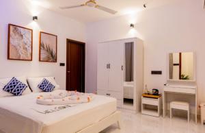 a white bedroom with a bed and a bathroom at Ocean Sunset in Dhangethi