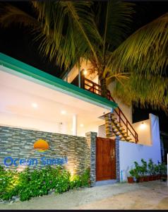 a building with a palm tree in front of it at Ocean Sunset in Dhangethi