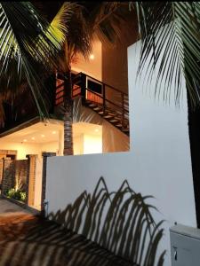 a palm tree casts a shadow on the side of a house at Ocean Sunset in Dhangethi