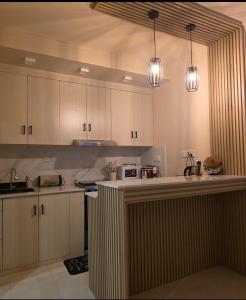 a kitchen with white cabinets and two lights at Ocean Sunset in Dhangethi