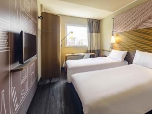 a hotel room with two beds and a flat screen tv at ibis Sao Paulo Ibirapuera in Sao Paulo