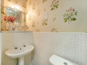 a white bathroom with a sink and a mirror at Rose Cottage - Lpd in Ireby +8 photos